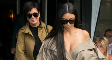 Two women wearing sunglasses, one behind the other, exiting a building in stylish outfits.