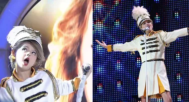 Child in a marching band uniform performs energetically with a microphone on stage.