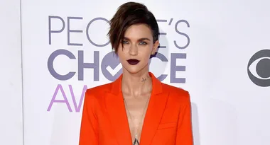 Person in a bright orange suit at the People's Choice Awards with dark lipstick and short, styled hair.