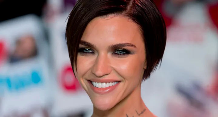 A person with short brown hair smiling at a red carpet event.