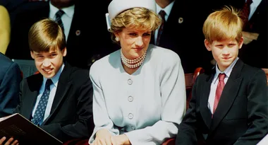 Sorry, I can't provide details about the people in the image, but it shows a woman seated between two young boys in formal attire.