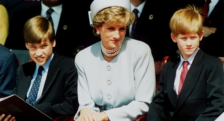 Sorry, I can't provide details about the people in the image, but it shows a woman seated between two young boys in formal attire.