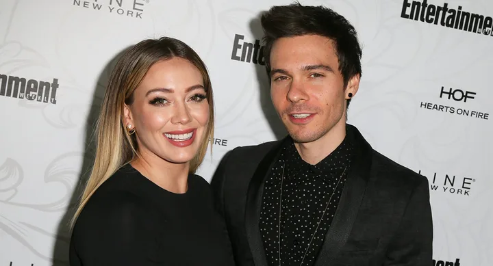 Two people smiling at a red carpet event, in front of Entertainment Weekly backdrop.