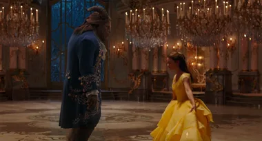 Belle dances with the Beast in a grand ballroom, adorned with chandeliers, in "Beauty and the Beast."