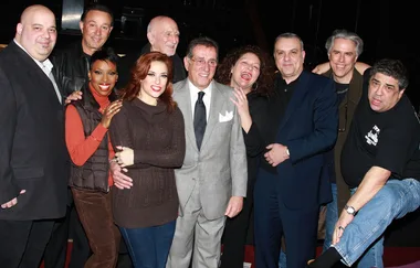 A group of ten people, dressed casually, posing happily together indoors.