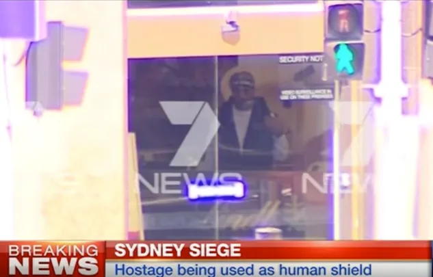 Sydney Siege news broadcast showing a man inside a building with a "Breaking News" banner at the bottom.