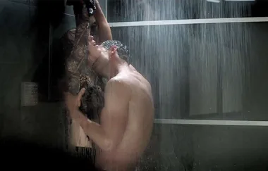 Couple embracing passionately under a shower, intimate scene with water cascading over them.