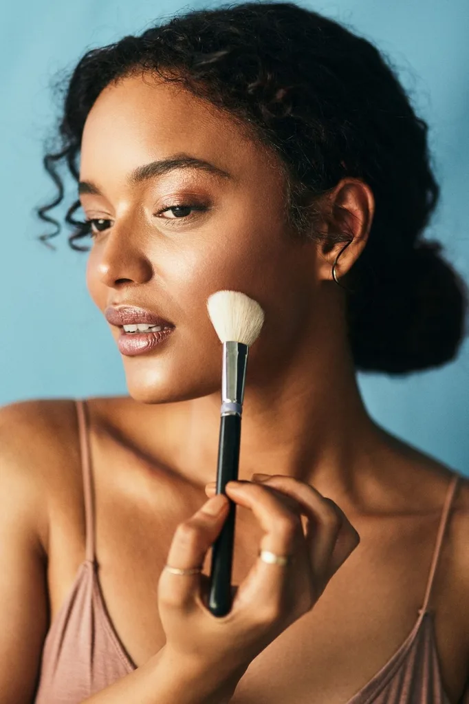 black woman applying foundation