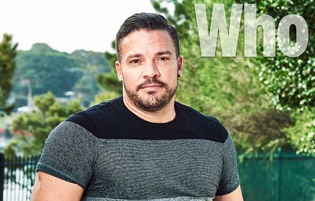 Man with short hair and beard outdoors, wearing a striped shirt. The word "Who" appears at the top right.