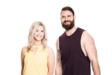 Man in a sleeveless black shirt and woman in a yellow top smiling at the camera against a white background.