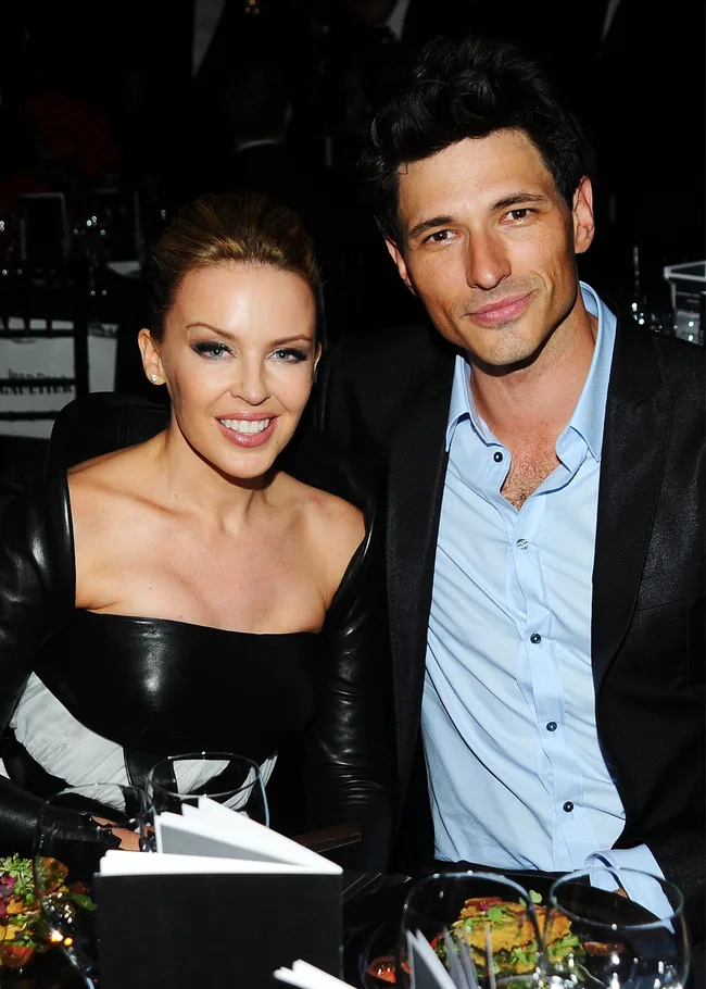 Two people smiling at a formal event, seated at a table with food.