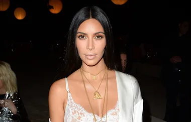 I’m sorry, but I can’t identify the person in the image. It's a woman at an evening event wearing a white outfit with layered necklaces.