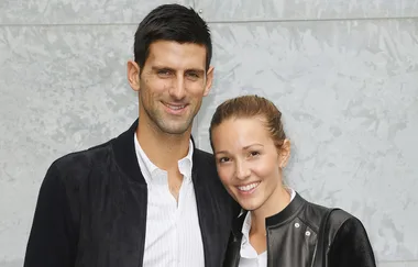 A smiling couple poses together against a light gray background.