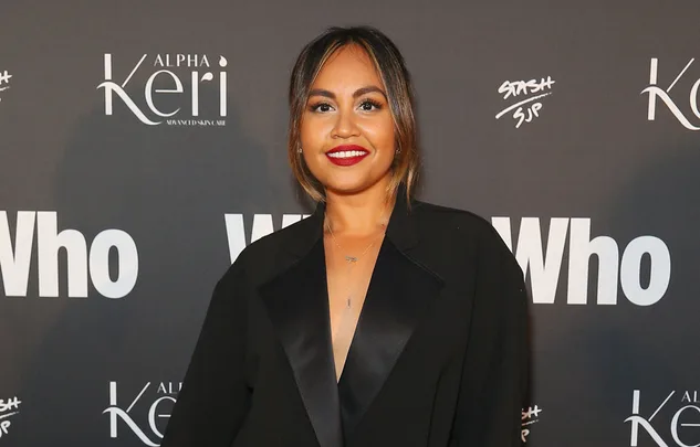 Woman in black blazer posing at an event with "Who" magazine backdrop.