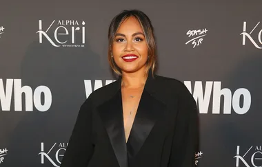 Woman in black blazer posing at an event with "Who" magazine backdrop.