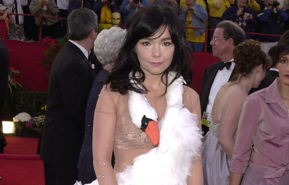 Woman wearing a swan dress on the red carpet at an event, surrounded by people in formal attire.