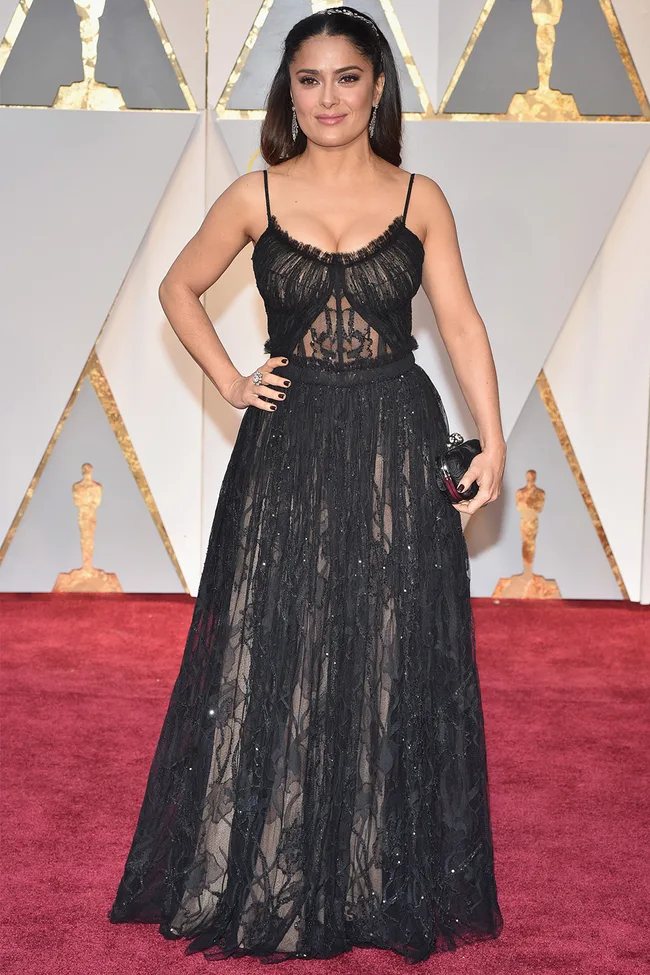 Woman in a black sheer gown on the red carpet at an awards event.