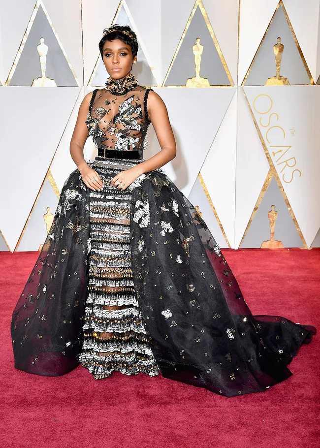 Woman in ornate black and silver gown on Oscars red carpet.