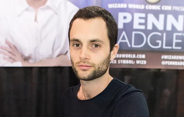Man with short dark hair and beard standing in front of a banner at a convention.