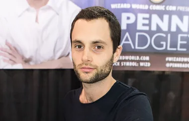 Man with short dark hair and beard standing in front of a banner at a convention.
