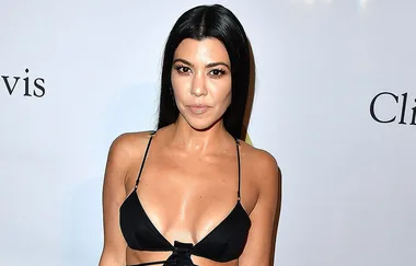 I don’t know who this is, but the image shows a woman in a black top on a red carpet with a white background.