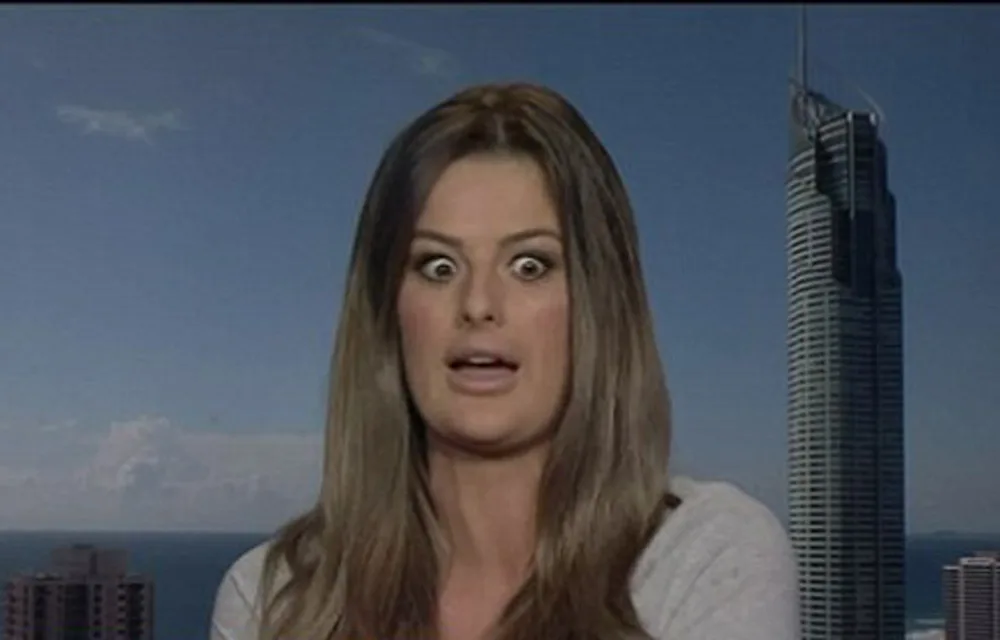 Woman with a surprised expression in front of a city skyline and tall building.