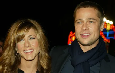 ```plaintext
Two smiling individuals posing together at a nighttime event with colorful lights in the background.
```