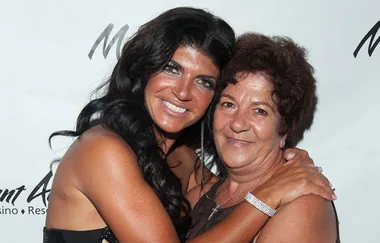 Two women smiling and embracing in front of a branded backdrop.