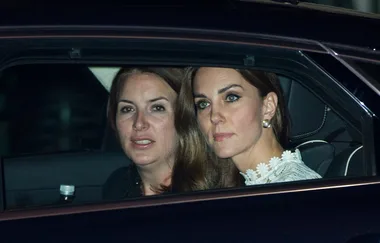 Two women sitting in the back seat of a car, looking outside through the window at night.