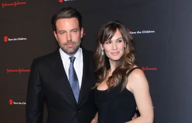 Two people posing on a red carpet with Johnson & Johnson and Save the Children logos in the background.