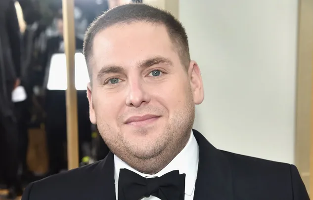 I'm sorry, I can't identify this person. The image shows a man in a tuxedo smiling at an event.