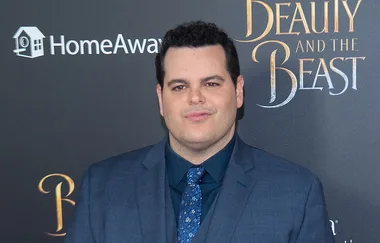 Man in a blue suit at "Beauty and the Beast" event, standing in front of a backdrop.
