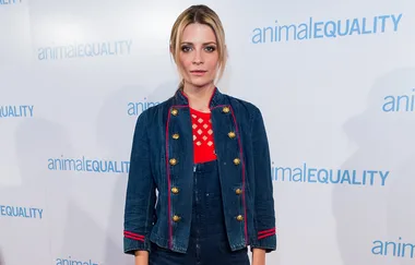 A person in a denim outfit stands in front of an "Animal Equality" backdrop.