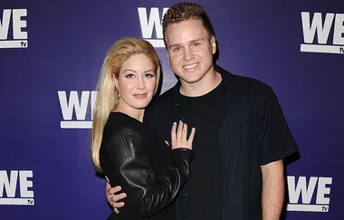 Couple posing on the red carpet at a WE TV event, with a purple backdrop featuring the WE TV logo.
