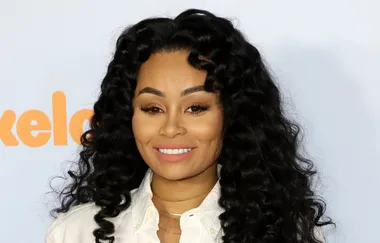 A person with long, wavy black hair smiles at an event with a Nickelodeon logo in the background.