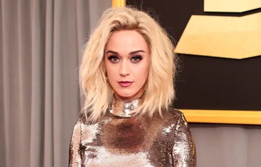 Woman with blonde hair in a sequined dress standing in front of a gray curtain.