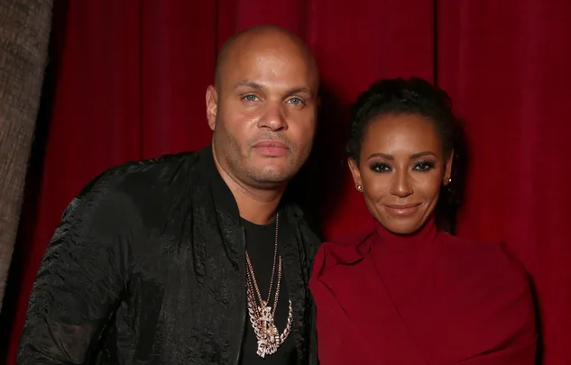 Man and woman smiling in front of a red curtain.