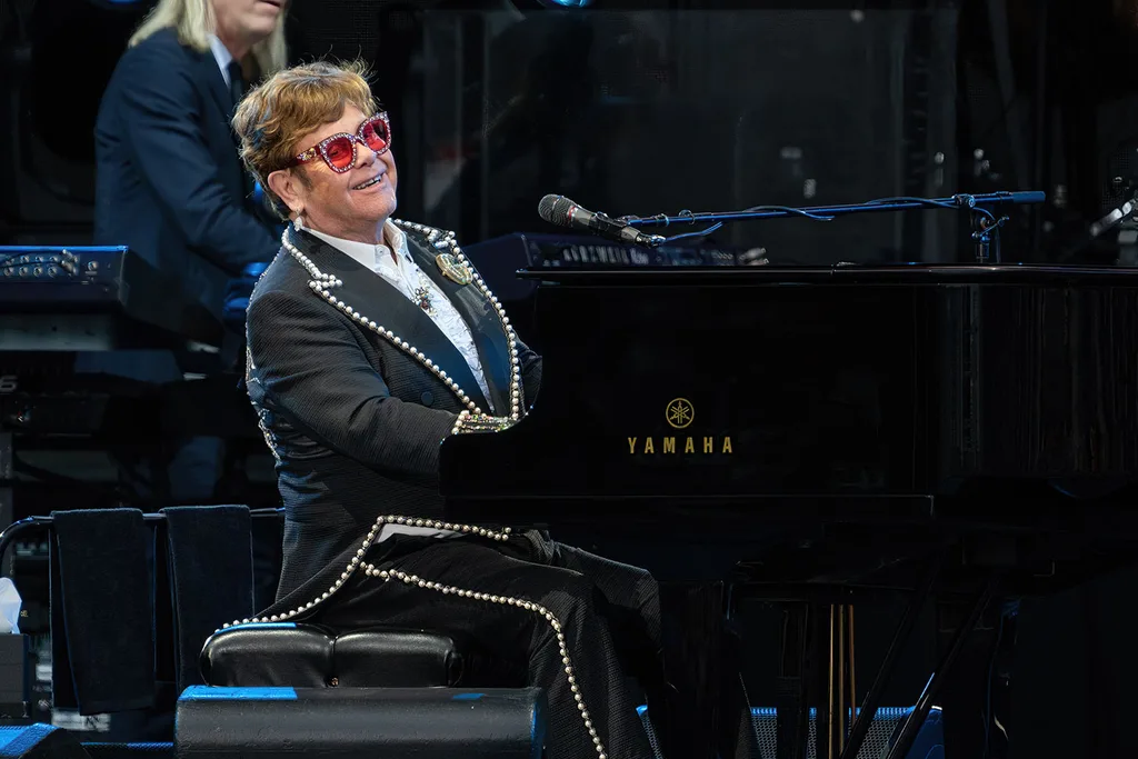 Elton-john-playing-piano-on-stage-in-black-studded-suit
