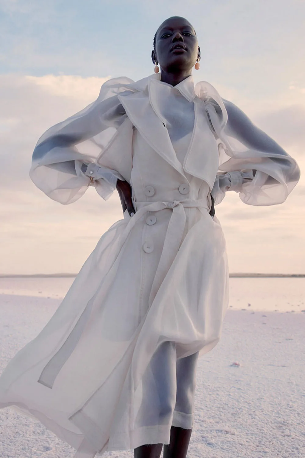 A-woman-wearing-a-flowy-white-organza-coat-from-Aje