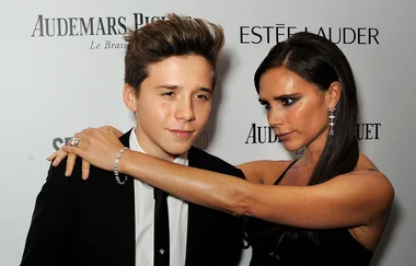 I don't know who these people are, but the image shows a woman placing her arms around a young man's shoulders at an event.