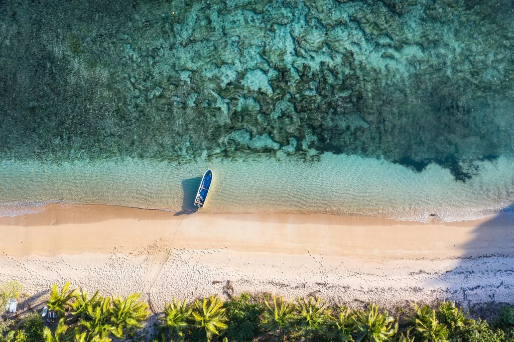 aerial-shot-of-fiji-featuring-blue-waters-white-sands-palm-trees-and-a-boat