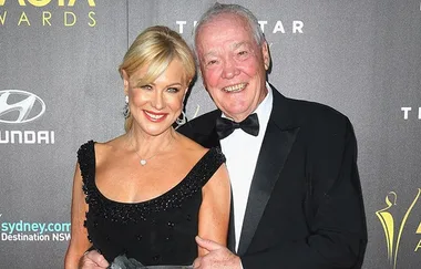A woman and man in formal attire smile at the AACTA Awards.
