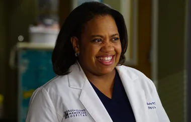 Doctor in a white coat smiles, "Grey Sloan Memorial Hospital" text visible on coat.