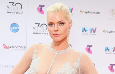 Woman in a sheer, embellished dress on the red carpet at the ARIA Awards 2016, with logos in the background.