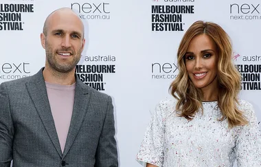 Two individuals at the Melbourne Fashion Festival, smiling at the camera, standing in front of the event backdrop.
