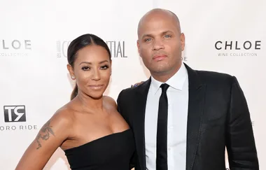 Two people smiling, dressed formally on a red carpet.