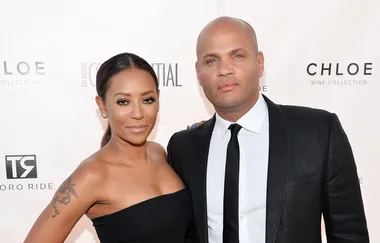 A woman in a strapless black dress and a man in a black suit pose together at a formal event.