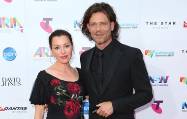 Man in a black suit and woman in a black dress with red roses at the 2015 ARIA Awards.
