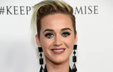 Woman with short blonde hair, large black earrings, and a nose ring, smiling against a white backdrop with text.