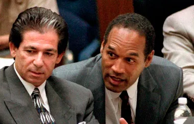 Two men in suits engaged in conversation at a formal event or legal setting.